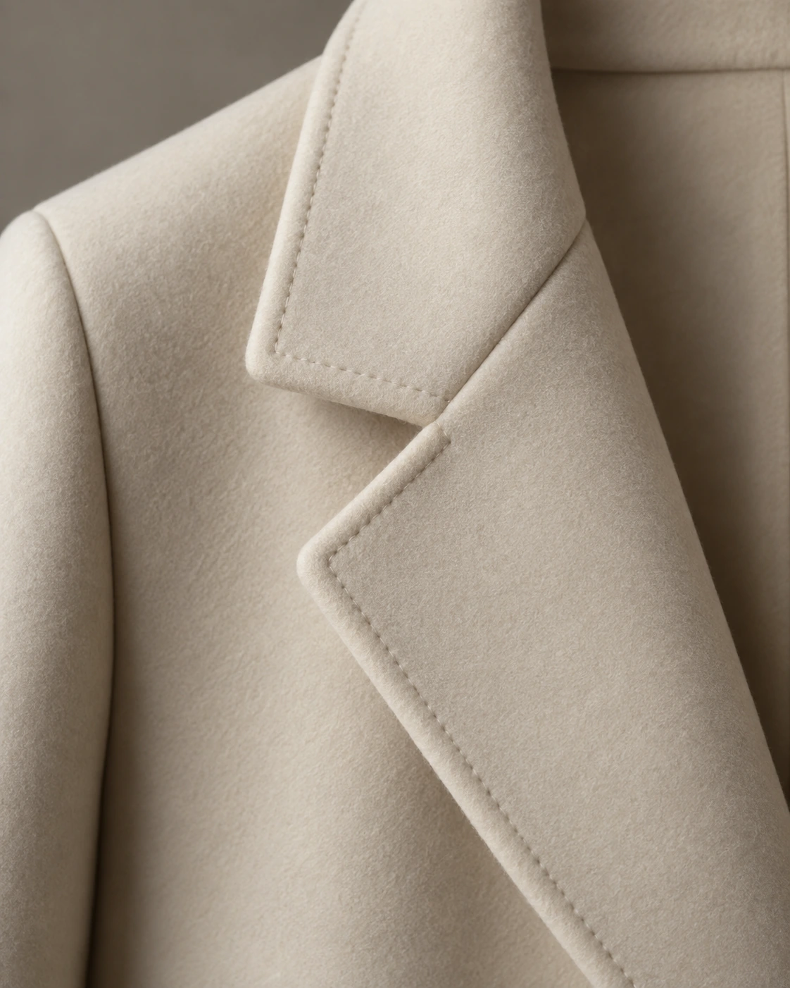 Close detail of a cream Melton wool lapel with a matte felted surface and neatly bound edge